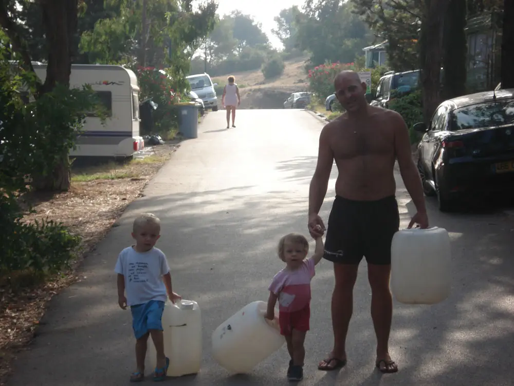 Vater und seine beiden Kinder auf dem Weg, die Wasserkanister beim Campingplatz Esterel Caravaning zu füllen