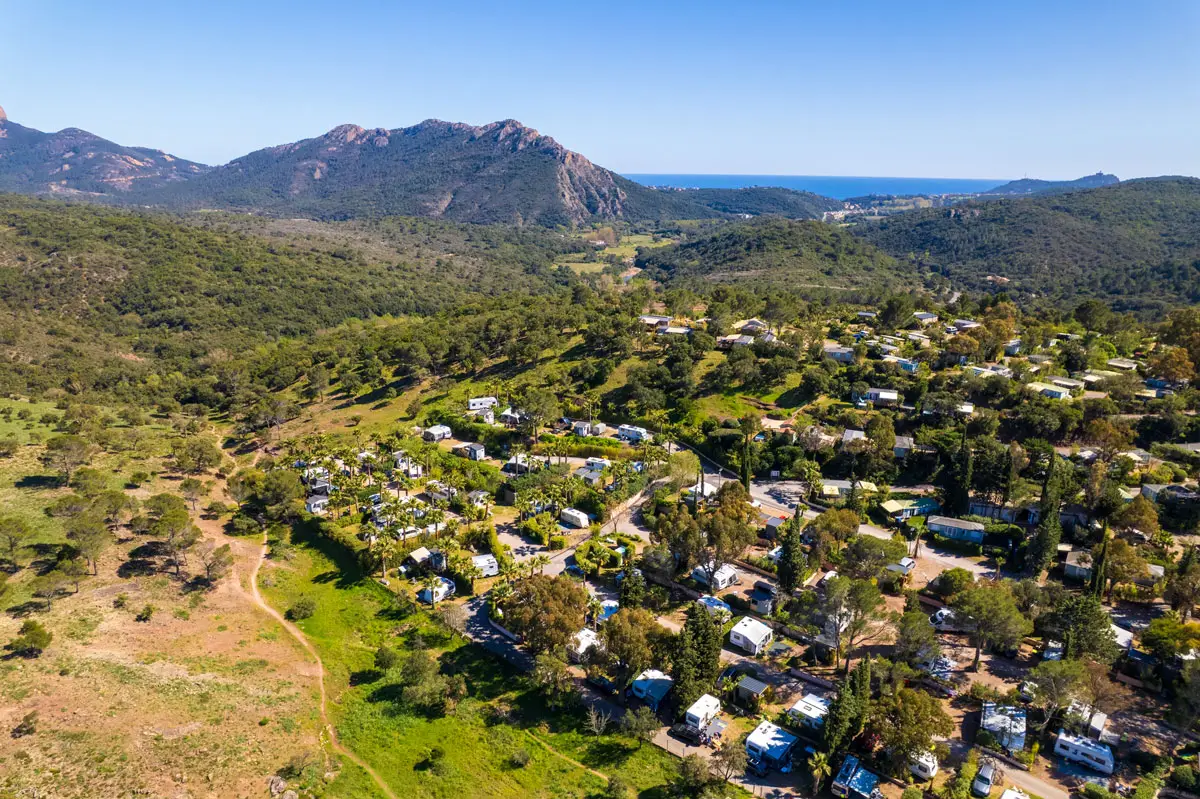 Luftaufnahme des Geländes von Esterel Caravaning in Agay: Stellplätze unter Pinien, das Esterel-Massiv und das Meer am Horizont