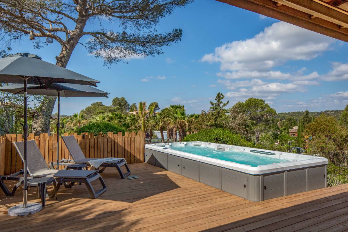 Privater Swim-Spa und Liegen auf der Holzterrasse des VIP Duo von Esterel Caravaning, unter Pinien